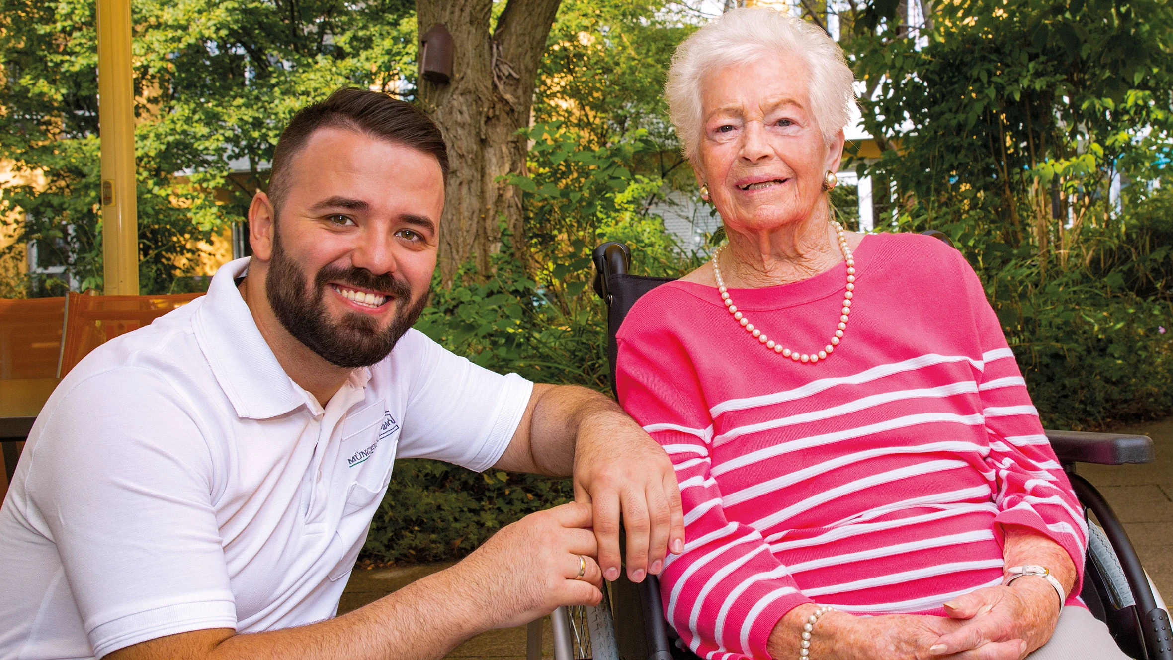 Caregiver with resident in the green courtyard