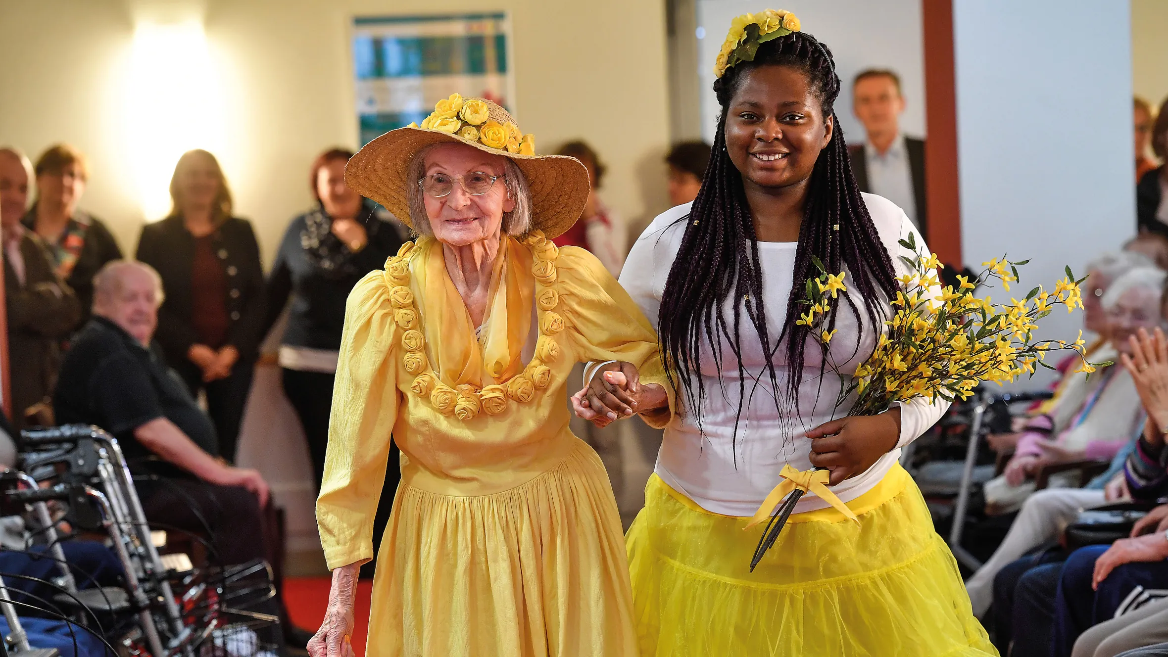 Modenschau Resident with yellow dress and big hat at the residence’s annual fashion show